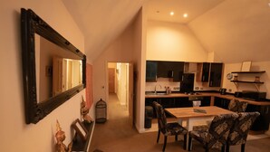 A modern kitchen with dark cabinets, a wooden dining table, and patterned chairs. - Centrally Located Modern Apartment in Llandudno (Llandudno)