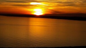 A sunset over a calm body of water with a clear horizon. - Centrally Located Modern Apartment in Llandudno (Llandudno)