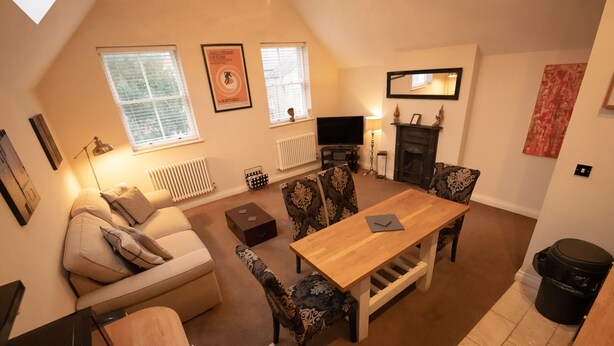 A cozy living room with a sofa, patterned chairs, a wooden table, a fireplace, and a television. - Centrally Located Modern Apartment in Llandudno (Llandudno)