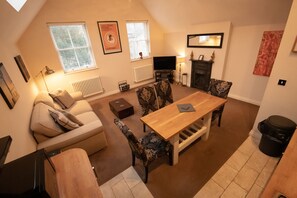 A cozy living room with a sofa, patterned chairs, a wooden table, a fireplace, and a television. - Centrally Located Modern Apartment in Llandudno (Llandudno)