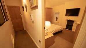 A bedroom with a bed, a bedside lamp, a TV, a fireplace, and a door. - Centrally Located Modern Apartment in Llandudno (Llandudno)