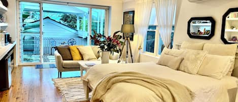 A bedroom with a large bed, a desk, and a view of the outside.