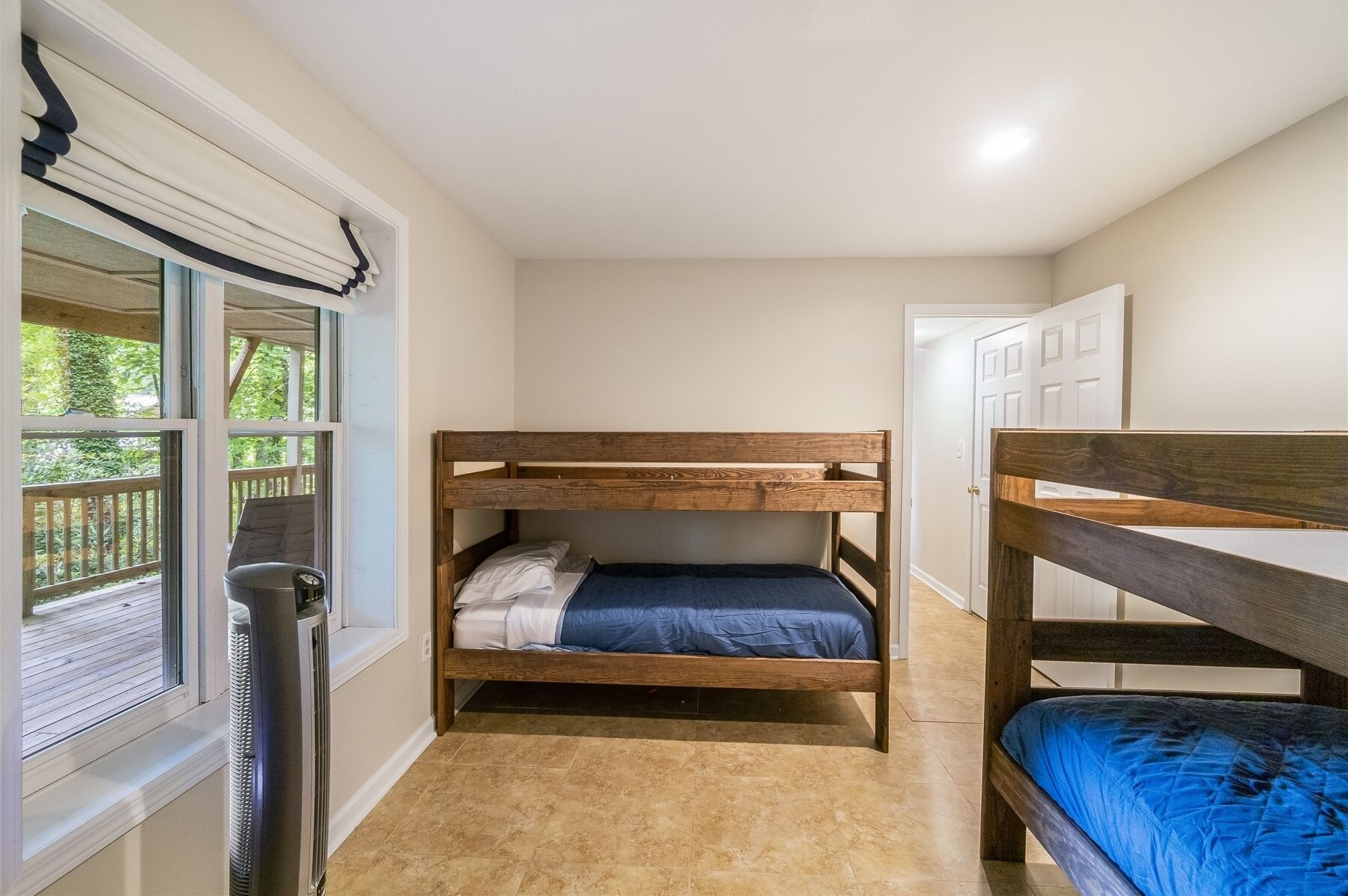 A small, compact room with a bunk bed, a radiator, and a window with blinds.