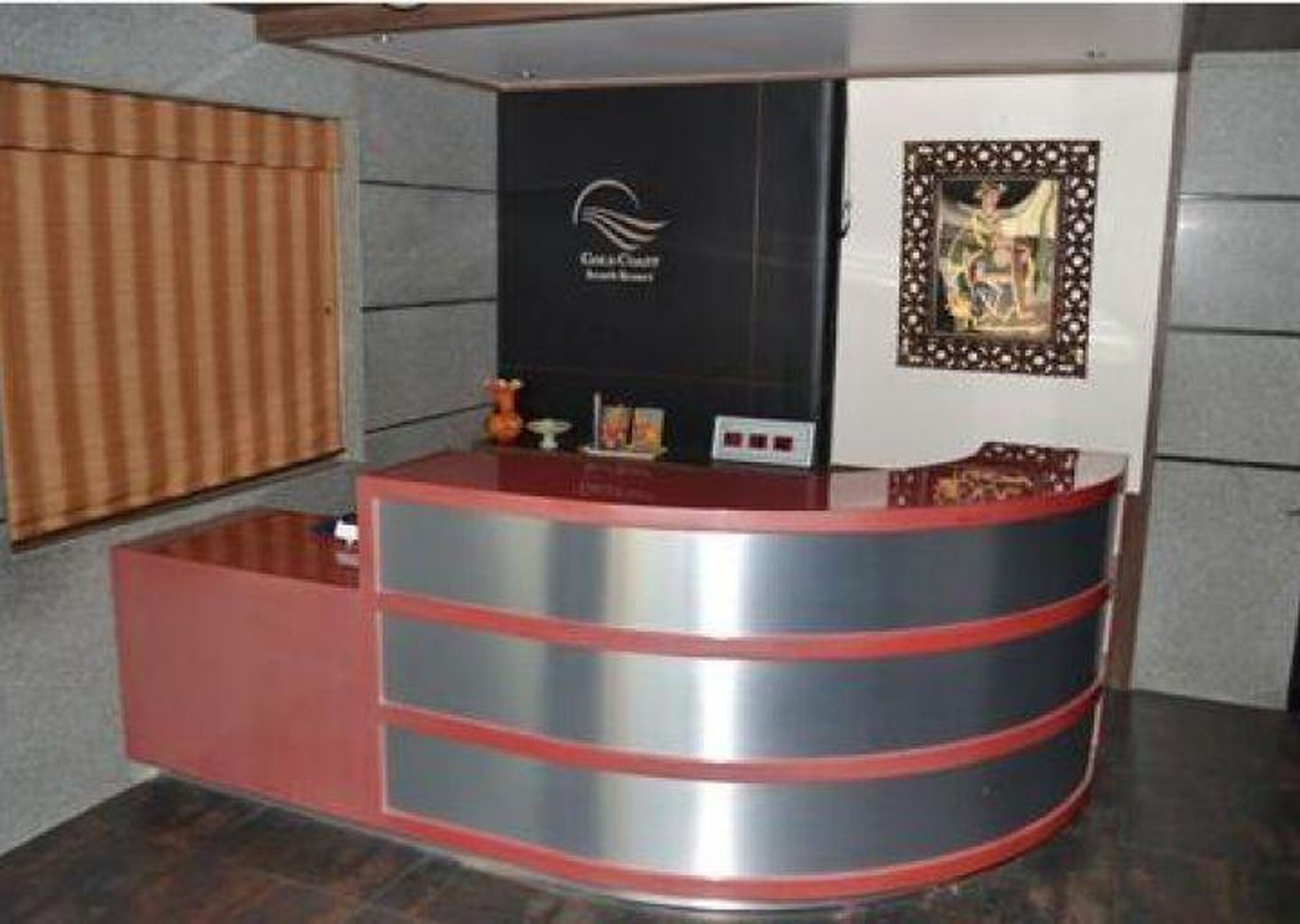 A reception desk with a logo, a framed picture, and a window with blinds.