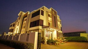 A multi-story hotel with a modern design, featuring a prominent entrance with a covered area and potted plants. - Gold Coast Beach Resort (Brahmagiri)