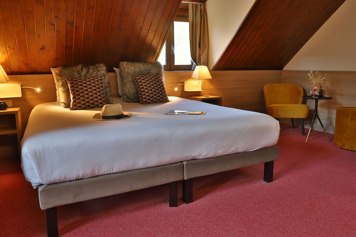 Ein Schlafzimmer mit einem großen Bett, Holzboden und einem kleinen Tisch mit einer Lampe.