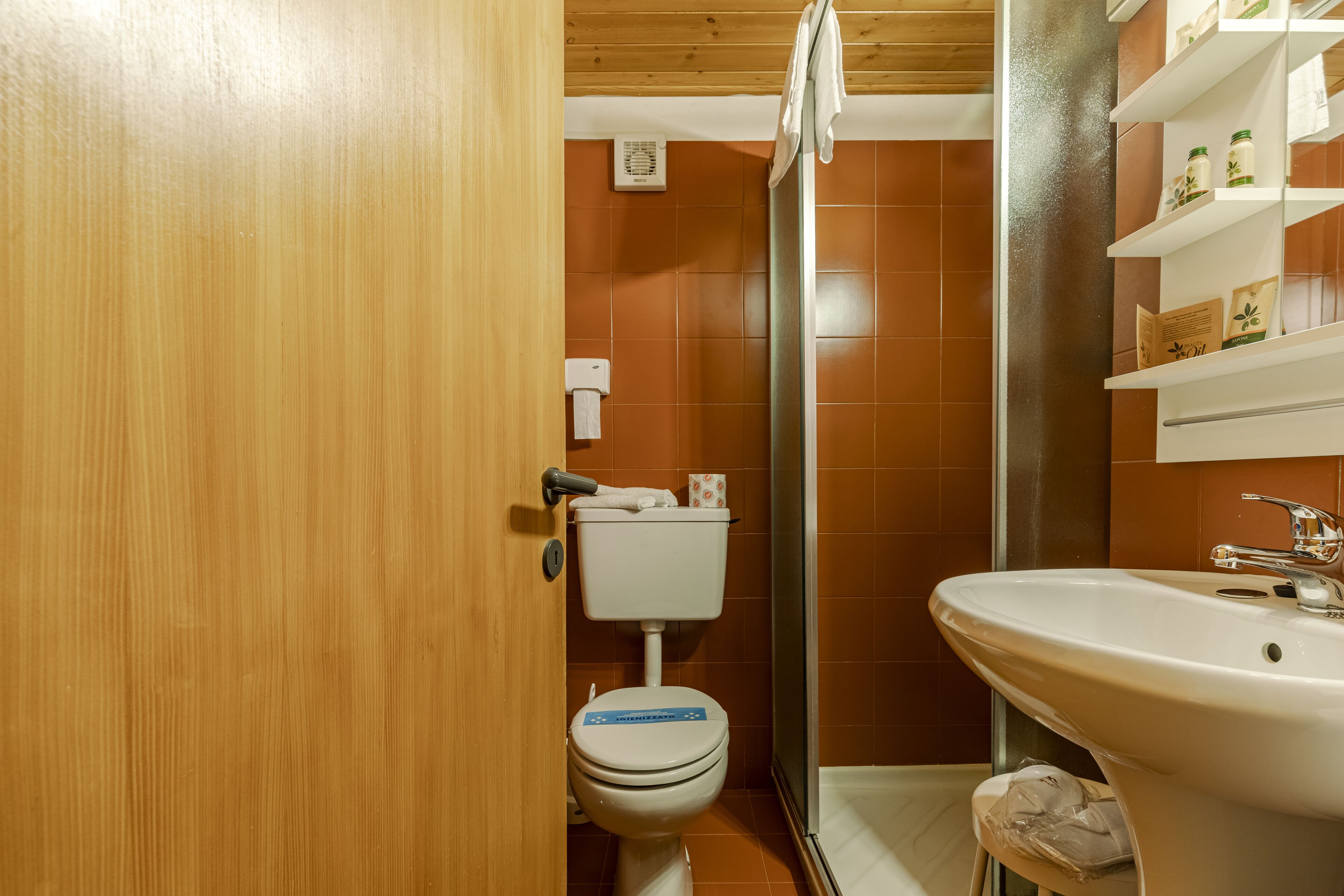 Un bagno con il water, un lavandino e mensole con articoli da toilette.
