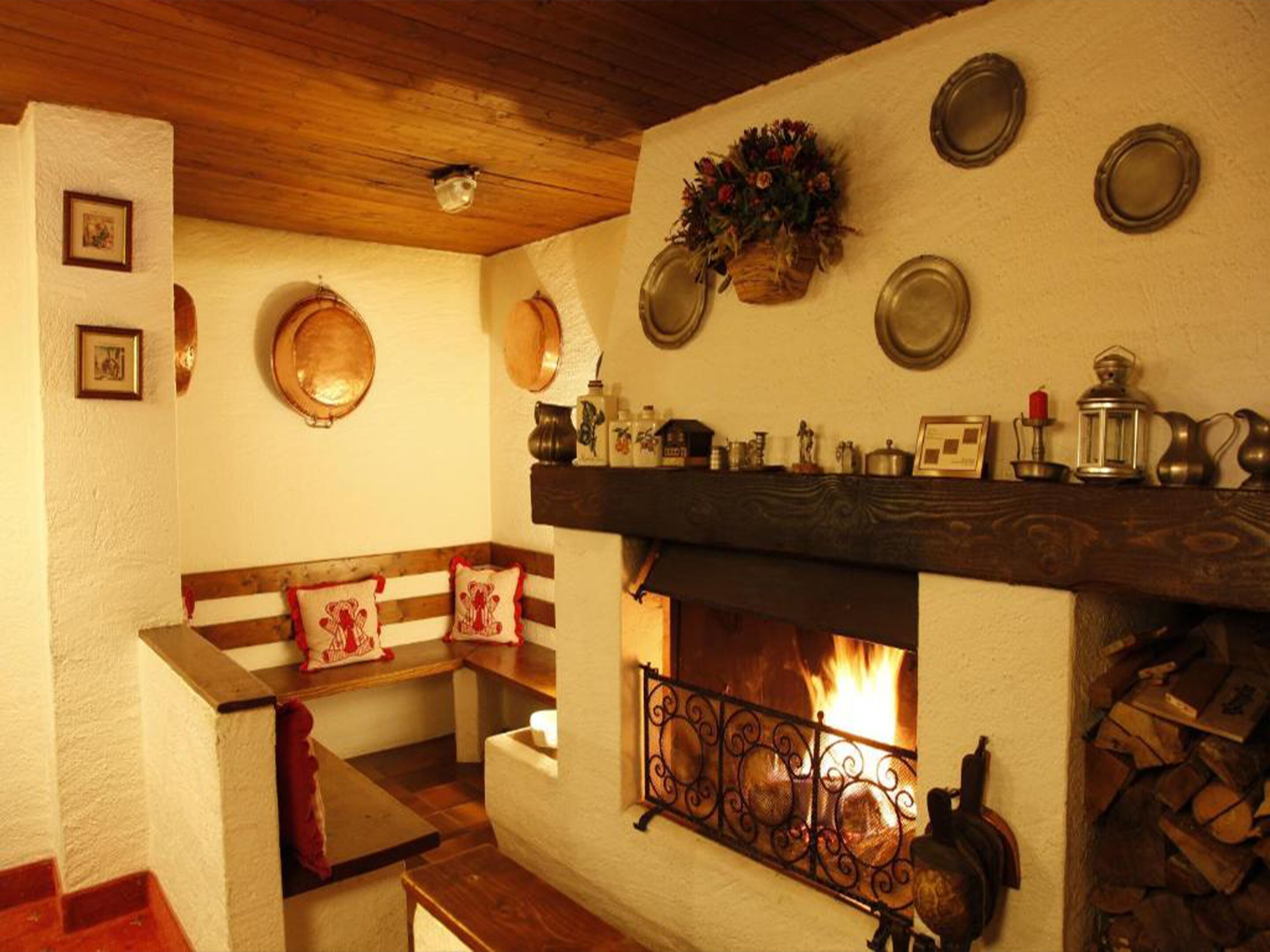 Una habitación acogedora con chimenea, un banco de madera y un repisa decorada con varios objetos.