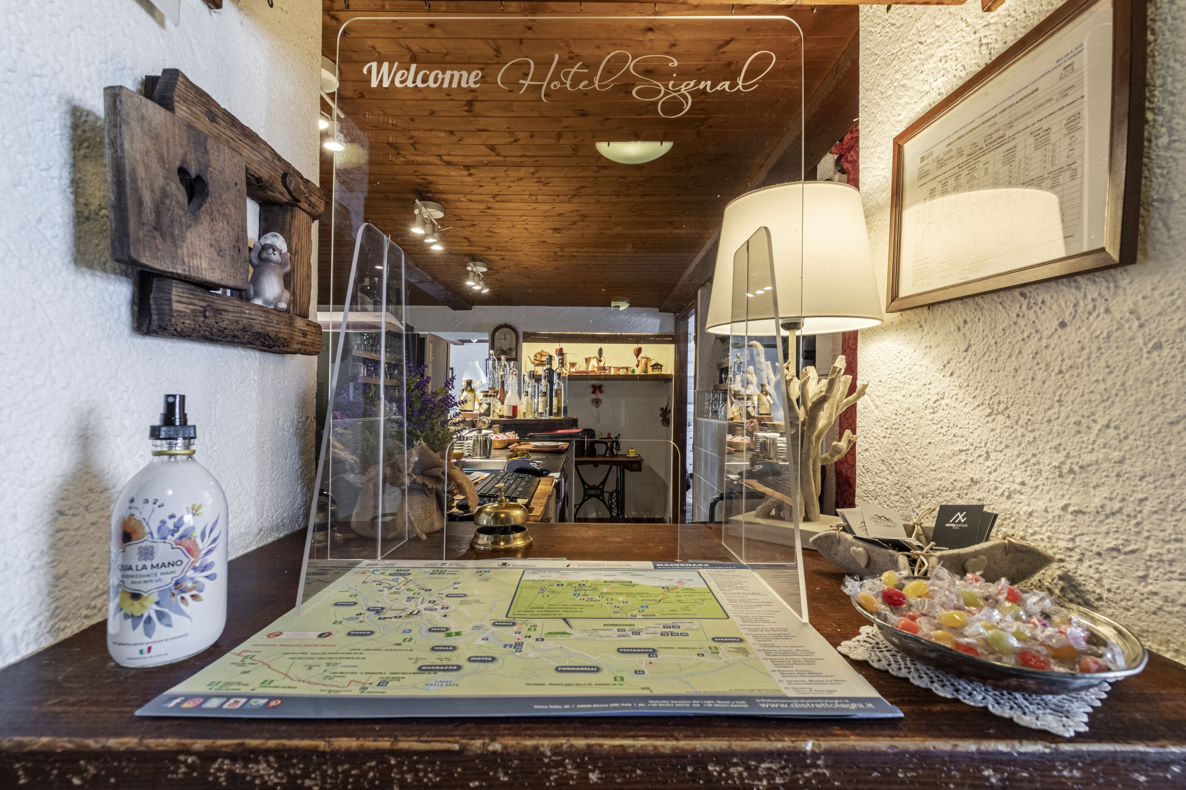 A reception desk with a map, a bottle of hand sanitizer, and a decorative bowl of candies.