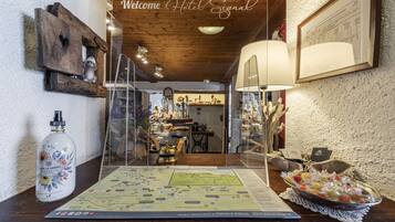A reception desk with a map, a bottle of hand sanitizer, and a decorative bowl of candies.