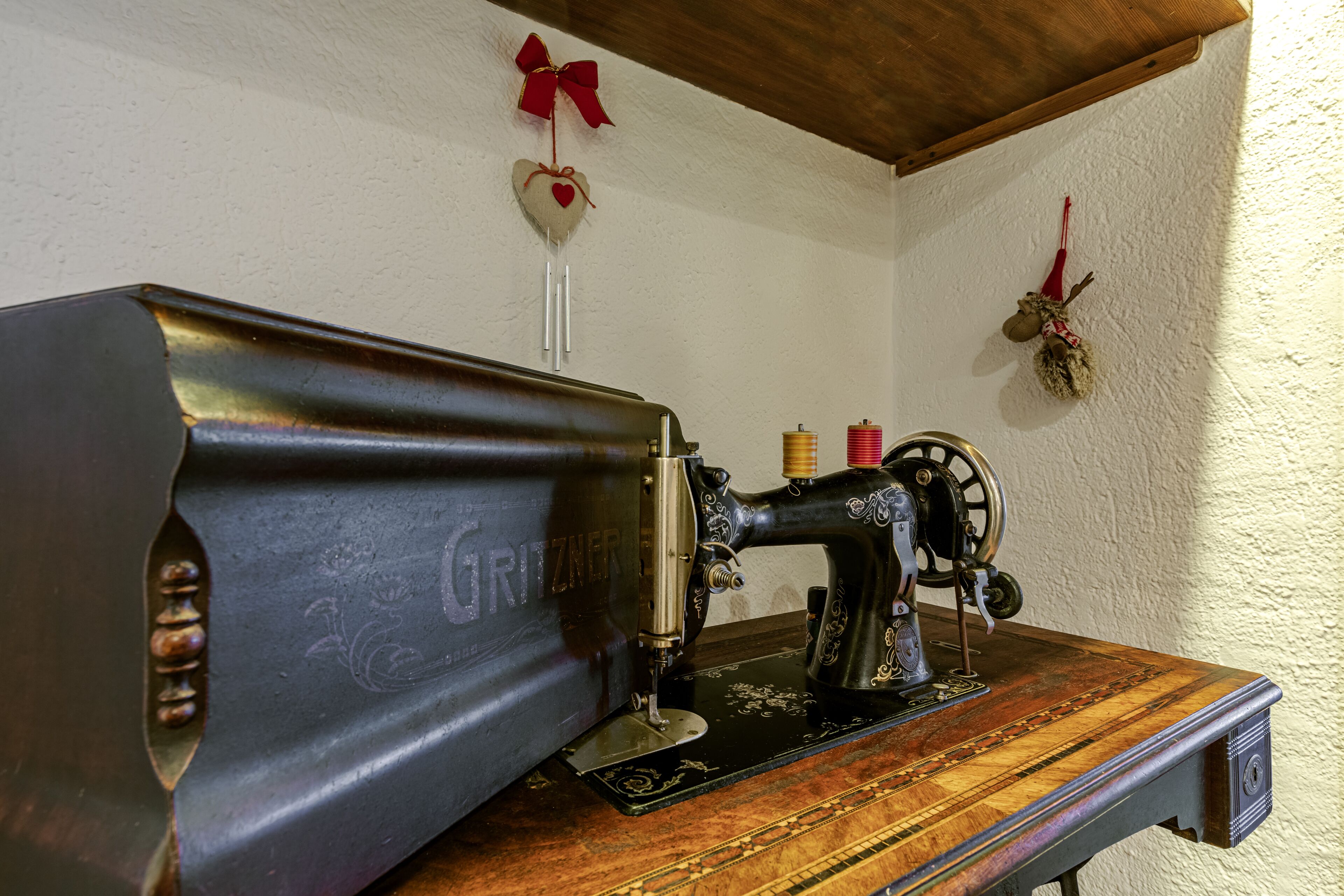 A vintage sewing machine on a wooden table with a white textured wall in the background.
