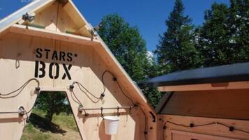 Una estructura de madera con techo inclinado y cableado visible, con un rótulo que dice 'STARS* BOX'.
