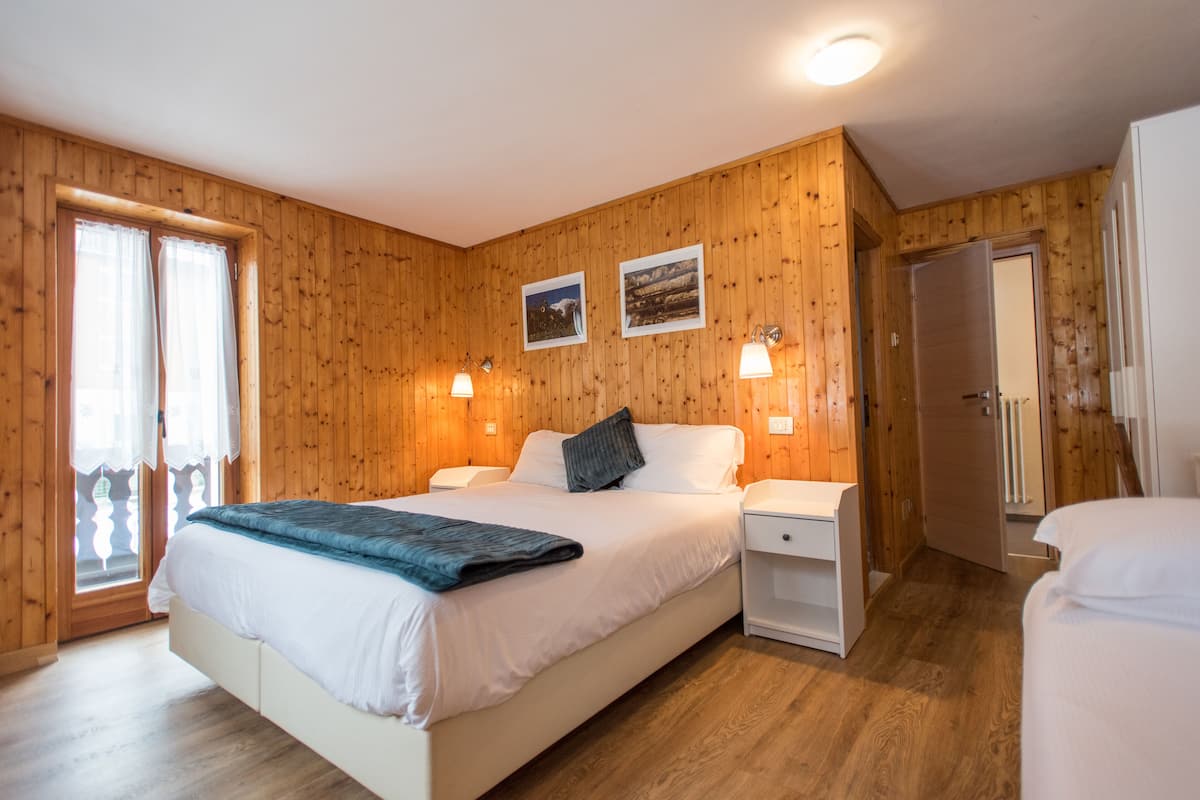 A wooden-paneled bedroom with a bed, bedside tables, and a door.