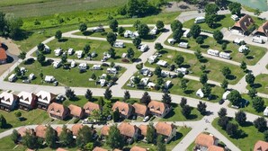 Una zona residencial con vehículos recreativos estacionados en filas ordenadas, rodeada de casas con techos de tejas rojas.