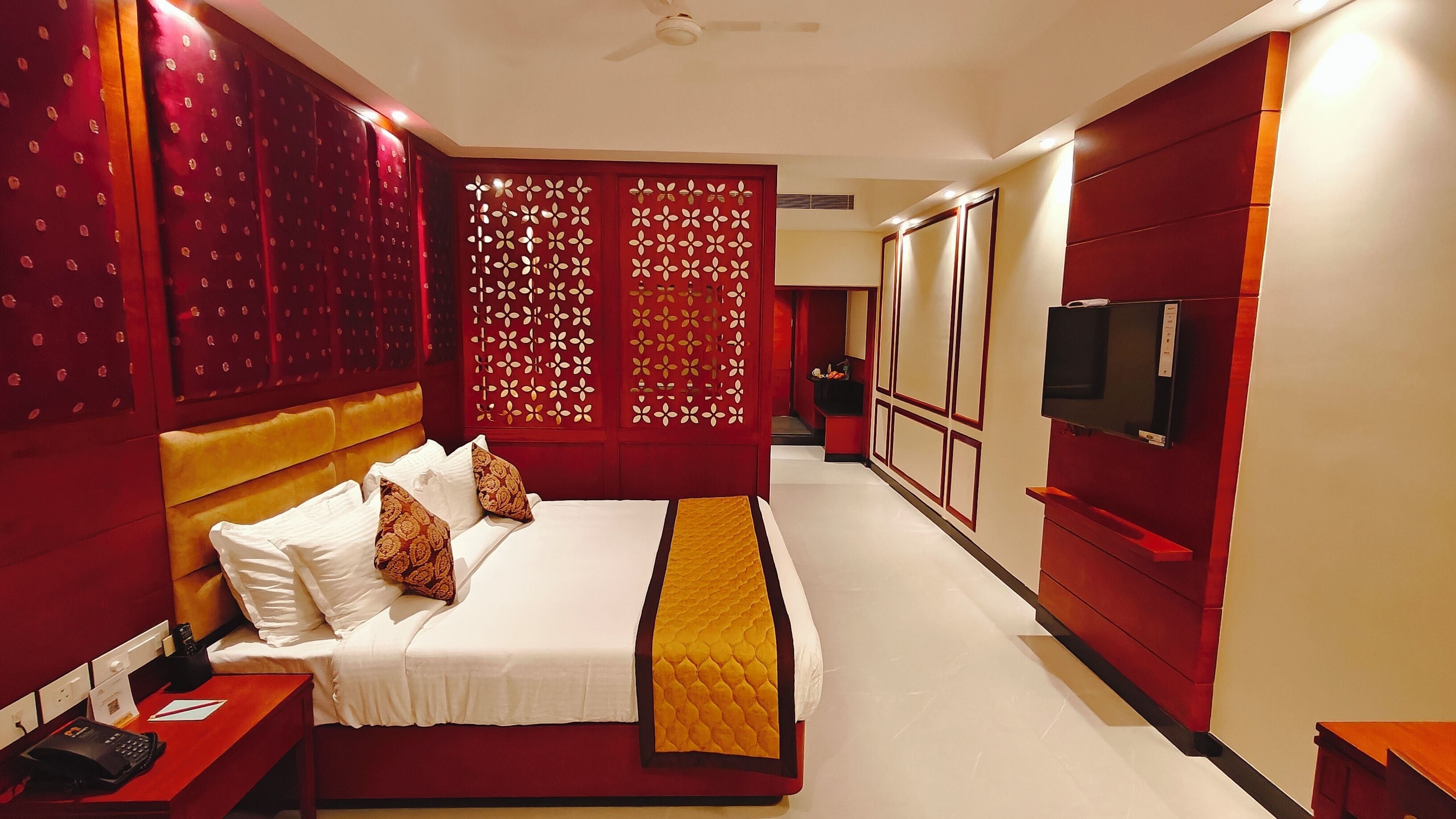 A hotel room with a large bed, a television, and a minibar.