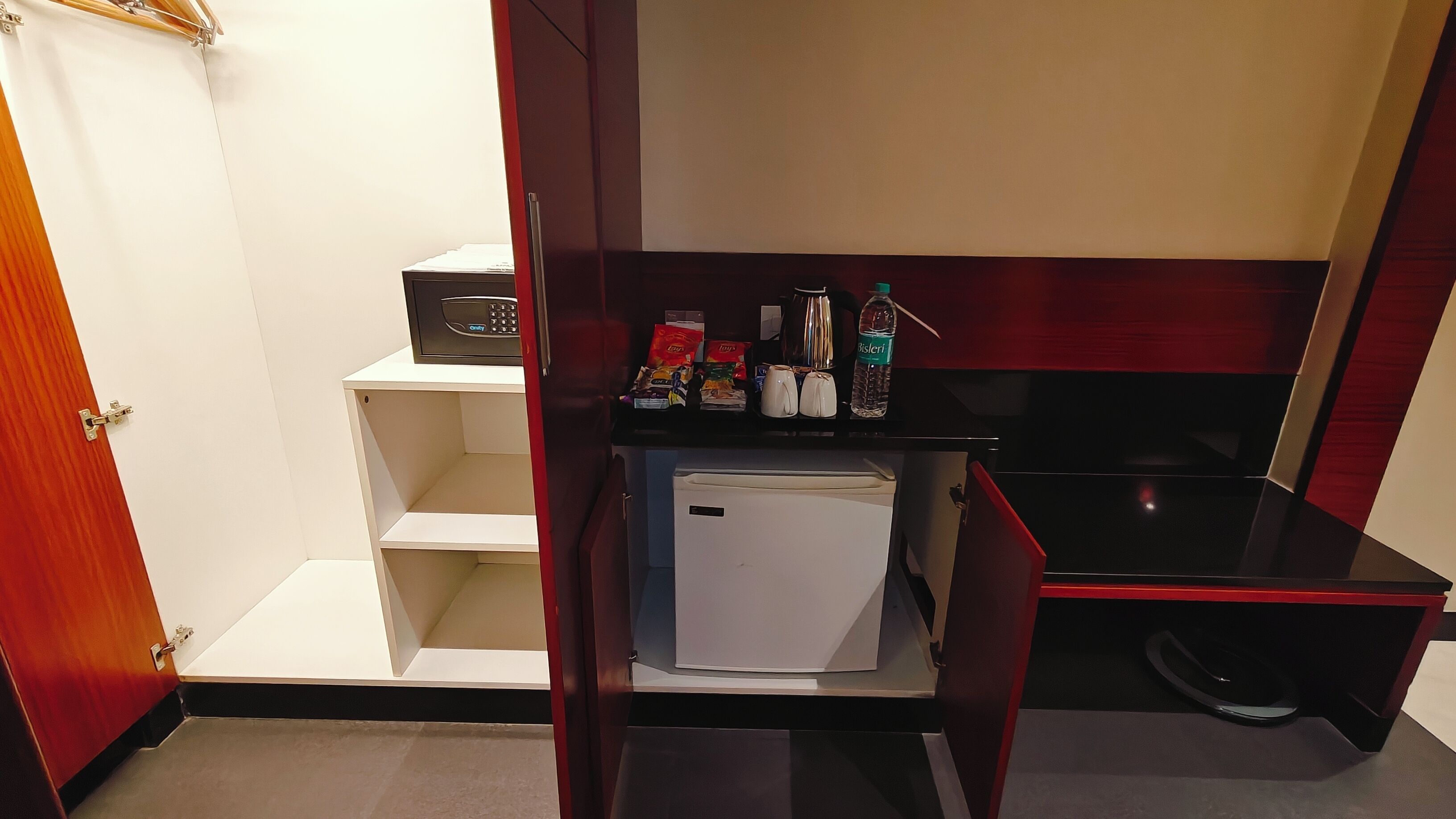 Une petite cuisine équipée d’un four à micro-ondes, d’un réfrigérateur et d’un petit plan de travail où se trouvent des en-cas et une bouilloire.