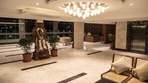 A lobby with a statue, seating area, and a reception desk.
