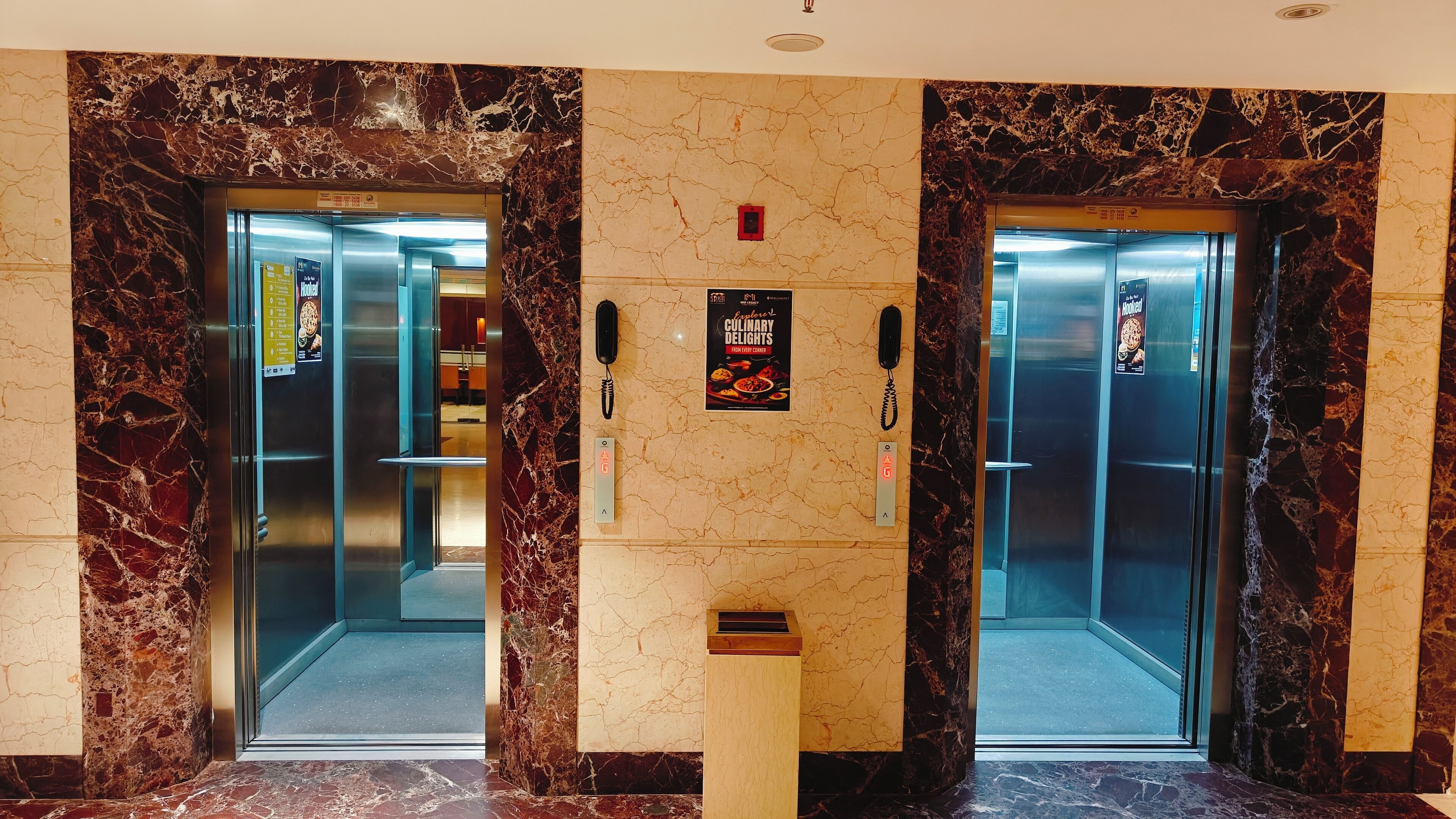 Two elevators with marble walls and a sign for 'Explorer Culinary Delights'.