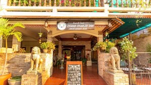 The entrance of Chang Charlie Inn Restaurant-Bar with a signboard, two lion statues, and potted plants. - Chang Charlie Inn (Pattaya)