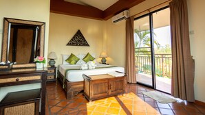 A hotel room with a bed, a desk, a mirror, a wall-mounted air conditioner, and a view of the outdoors through a sliding glass door. - Chang Charlie Inn (Pattaya)
