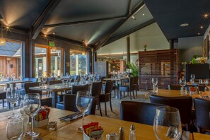 Enjoy a meal in our spacious dining area, where tables are set with wine glasses, cutlery, and condiments.
