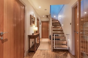 Staircase leads to an upper level, with a wooden door and glass door separating areas.