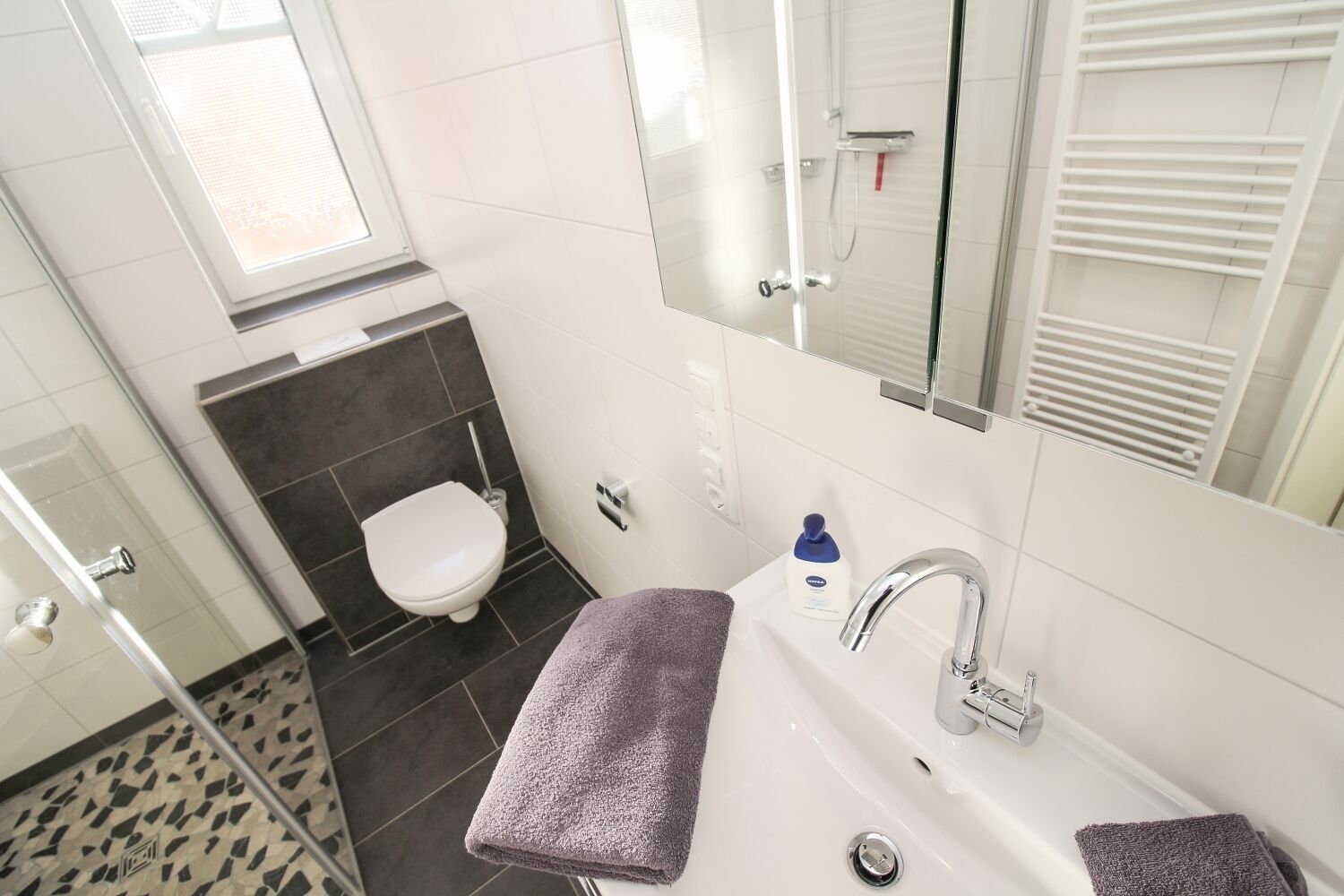 Un baño con lavamanos blanco, un espejo, inodoro y ducha.