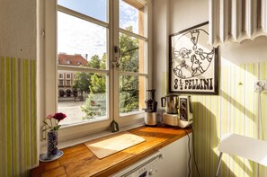 Enjoy a kitchen with a window view, coffee maker, and kettle, surrounded by a vase with flowers and a framed picture.