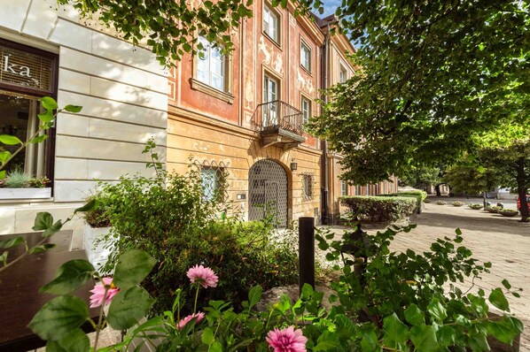 Experience the tranquil charm of this traditional urban retreat, featuring a balcony with a wrought-iron railing and lush greenery.