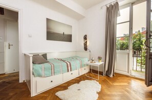 A bedroom with a bed, a small table, a painting, and a view of the outside. - Warsaw Concierge Studio Old Town Square (Warsaw)