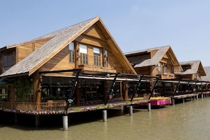 Wooden floating structures with balconies, connected by walkways, over a body of water. - Olive Tree Hotel Pattaya (Sattahip)