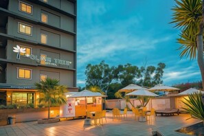 A hotel with outdoor seating and a sign reading 'OLIVE TREE'. - Olive Tree Hotel Pattaya (Sattahip)