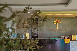 A reception area with a logo, a counter, and a sign indicating a 'Welcome & Welcome' message. - Olive Tree Hotel Pattaya (Sattahip)
