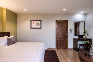 A hotel room with a bed, a desk, a chair, and a door. - Olive Tree Hotel Pattaya (Sattahip)