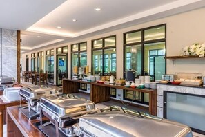 A buffet setup with multiple serving stations, a bar area, and a seating arrangement. - Olive Tree Hotel Pattaya (Sattahip)