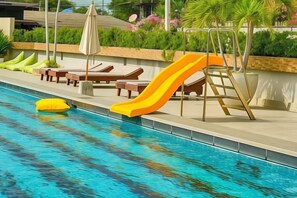 A swimming pool with a slide, lounge chairs, and a lifeguard stand. - Olive Tree Hotel Pattaya (Sattahip)