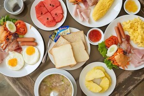 A table with various food items including plates of eggs, sausages, and sandwiches. - Olive Tree Hotel Pattaya (Sattahip)