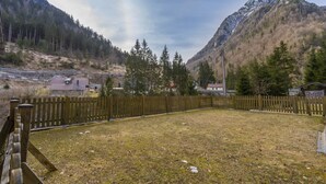 Ein eingezäunter Hof mit Bergblick, ein Holzzaun und ein Gebäude mit rotem Dach.