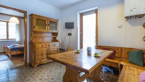 Ein Holzespeisesaal mit Stühlen, einer Bank, einem Schrank und einem Fernseher an der Wand.