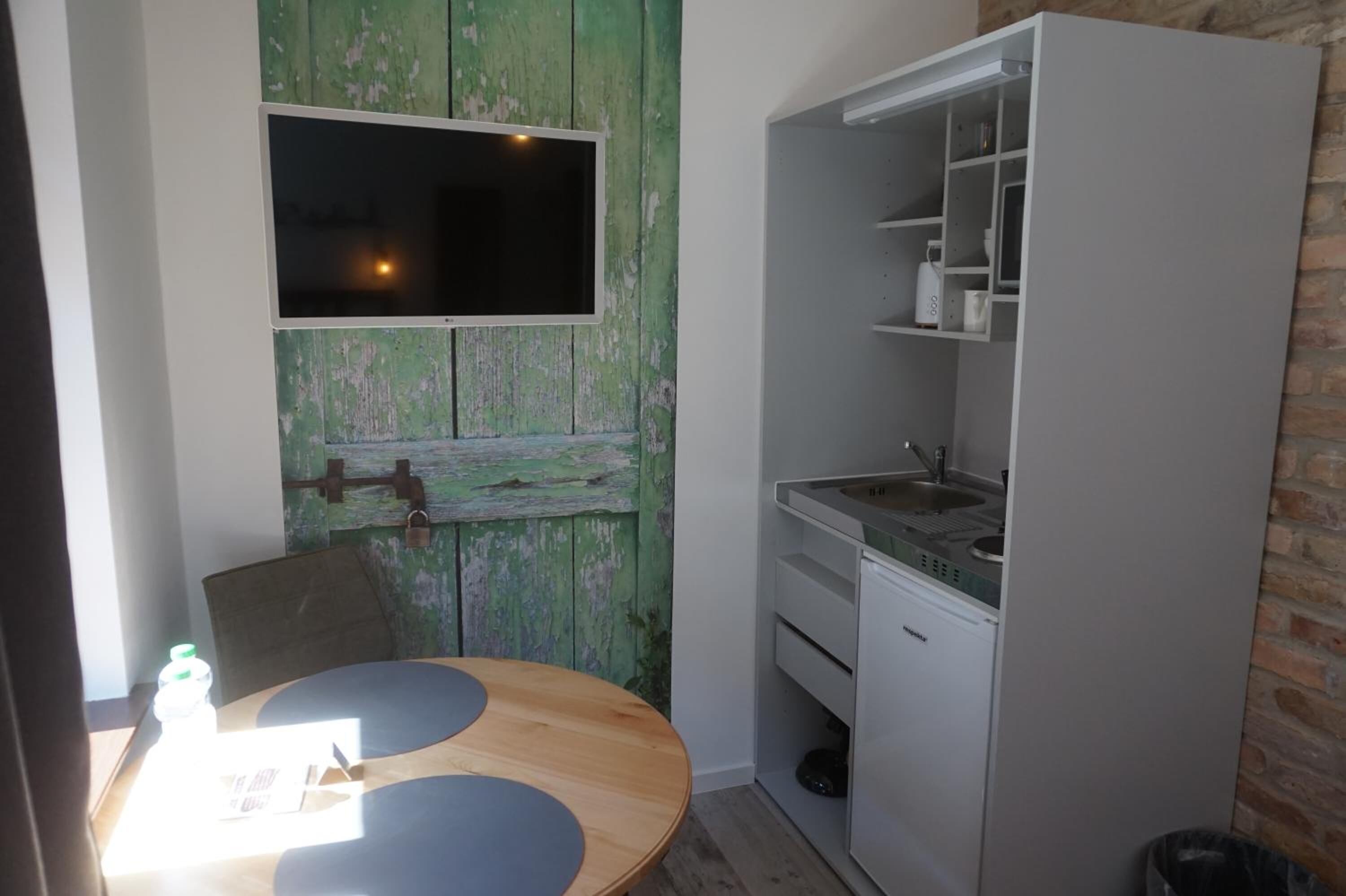 Una cocina compacta con un lavabo, un refrigerador pequeño y una mesa de madera con una silla.