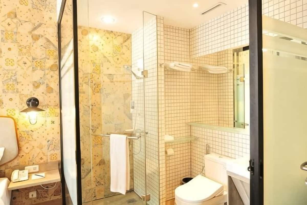 A bathroom with a shower, toilet, sink, and a mirror.