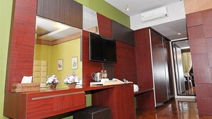 Una habitación de hotel con un escritorio de madera, un televisor de pantalla plana y un espejo grande.