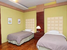 A hotel room with two single beds, wooden flooring, and a wooden wardrobe.