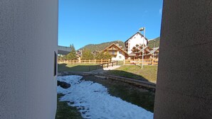 A view from a balcony overlooking a snow-covered path with wooden buildings in the background. - Mini studio with parking in Montgenèvre (Montgenèvre)