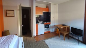A compact hotel room with a kitchenette, a bed, a TV, and a small seating area. - Mini studio with parking in Montgenèvre (Montgenèvre)