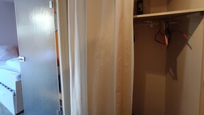 A hotel room with a bed, a wardrobe, and a shelf with items. - Mini studio with parking in Montgenèvre (Montgenèvre)