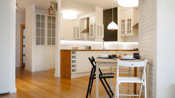 A modern kitchen with white cabinetry, a wooden countertop, and a dining area with a white table and chairs. - Warsaw Concierge Family Apartment (Warsaw)