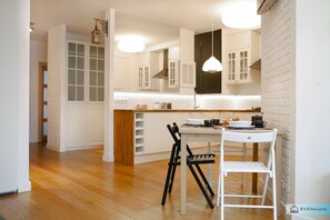 A modern kitchen with white cabinetry, a wooden countertop, and a dining area with a white table and chairs.