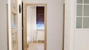 A hallway with wooden flooring, white walls, and a door with frosted glass panels. - Warsaw Concierge Family Apartment (Warsaw)