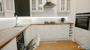 A modern kitchen with white cabinetry, a stainless steel range hood, a built-in dishwasher, and a black oven. - Warsaw Concierge Family Apartment (Warsaw)
